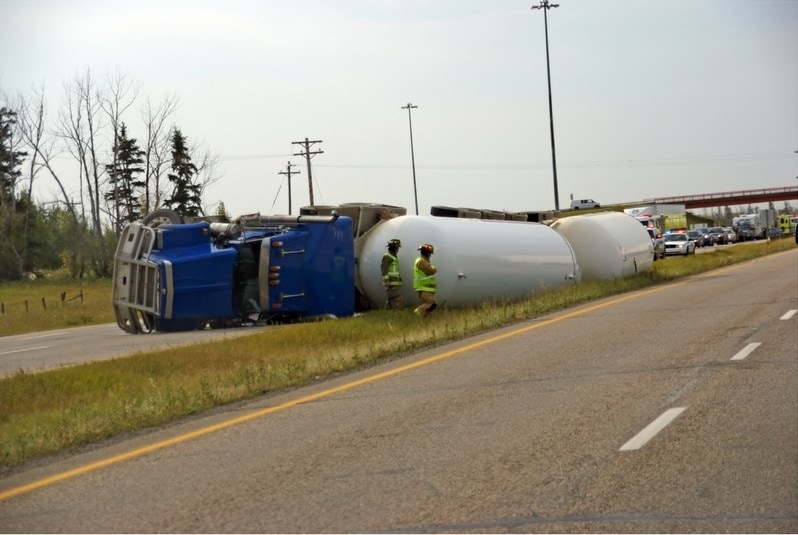 Overturned sem-truck on side of the highway.