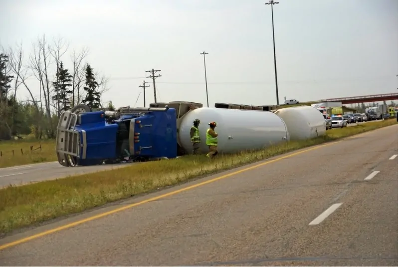 Overturned sem-truck on side of the highway.