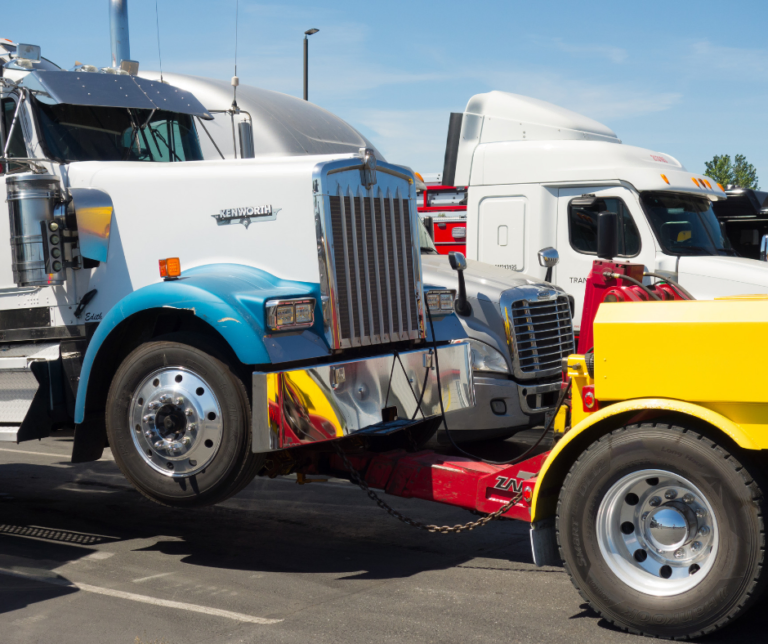 A white semitruck with a yellow tow truck, dealing with downtime claims.