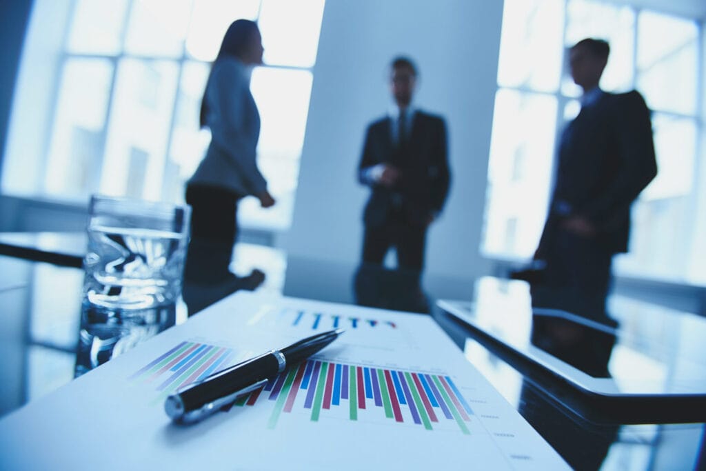 paper on desk with business people in background