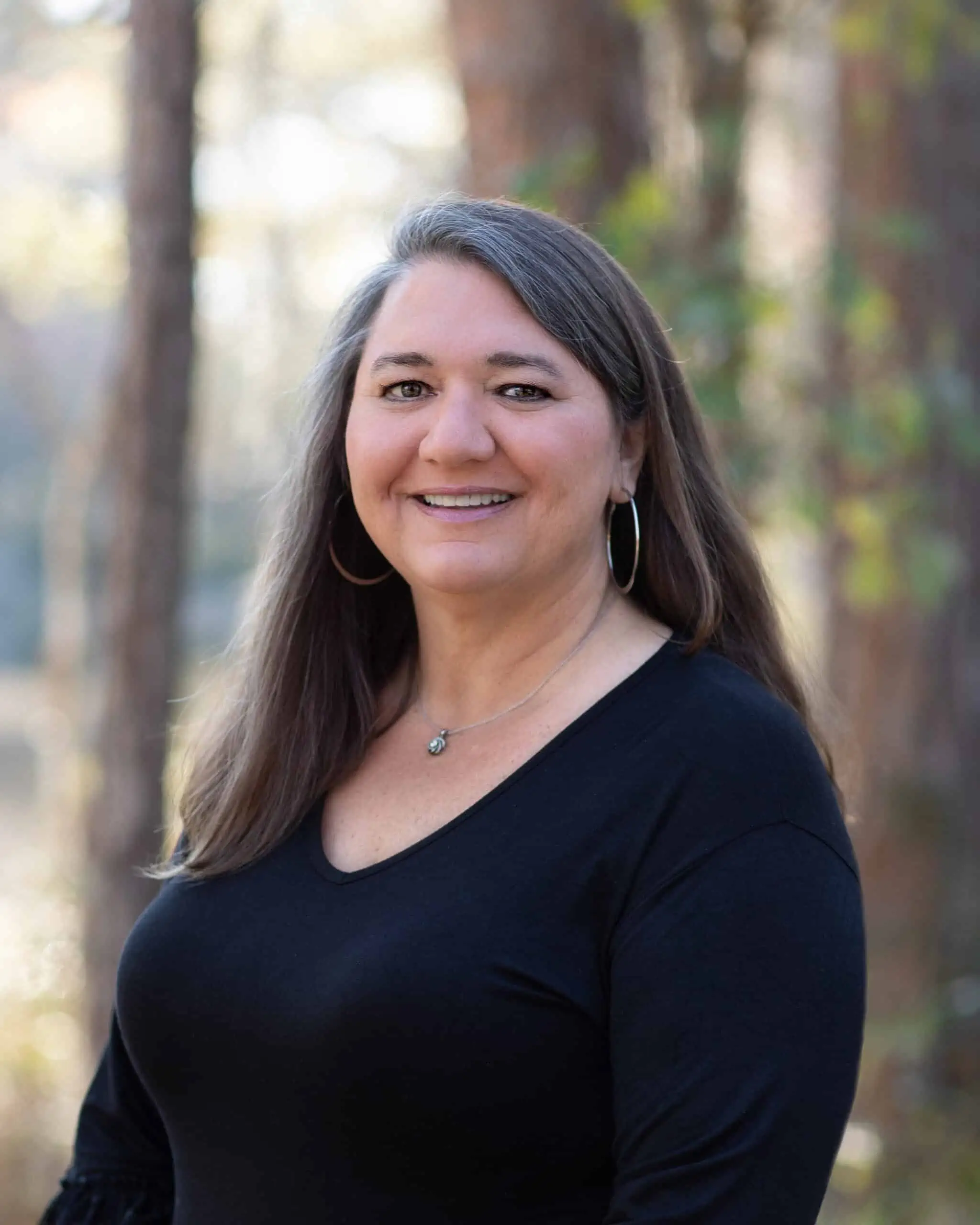 A woman in a black top standing in the woods.