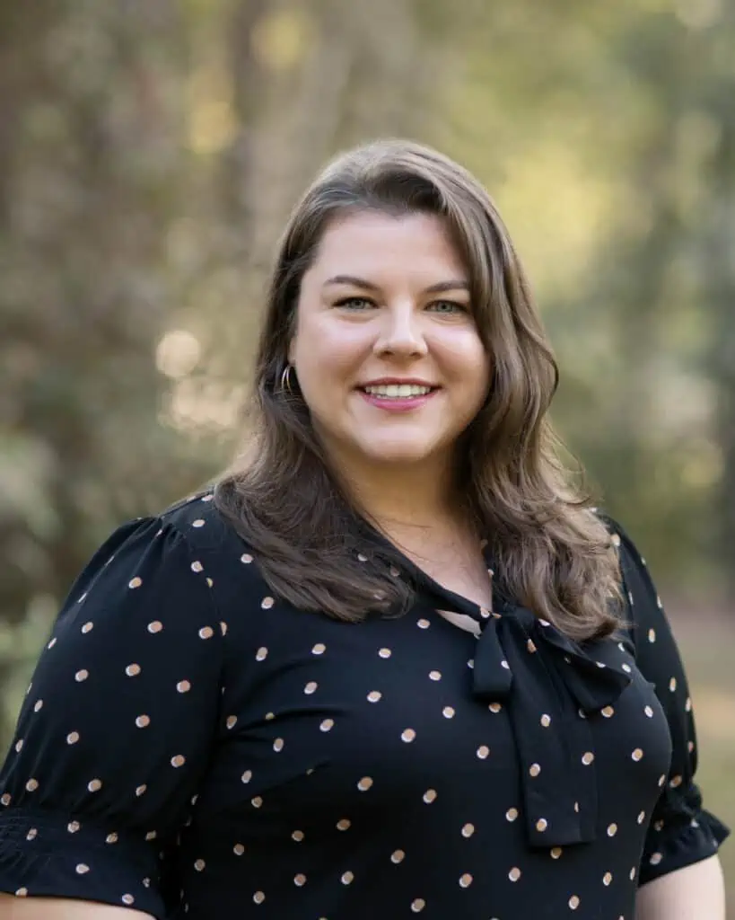 A smiling woman in a black polka dot dress.