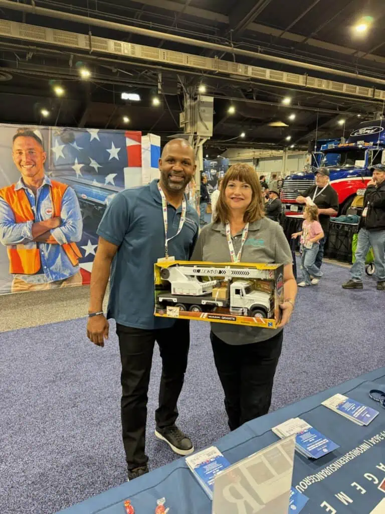 Two individuals at an event holding a model truck.