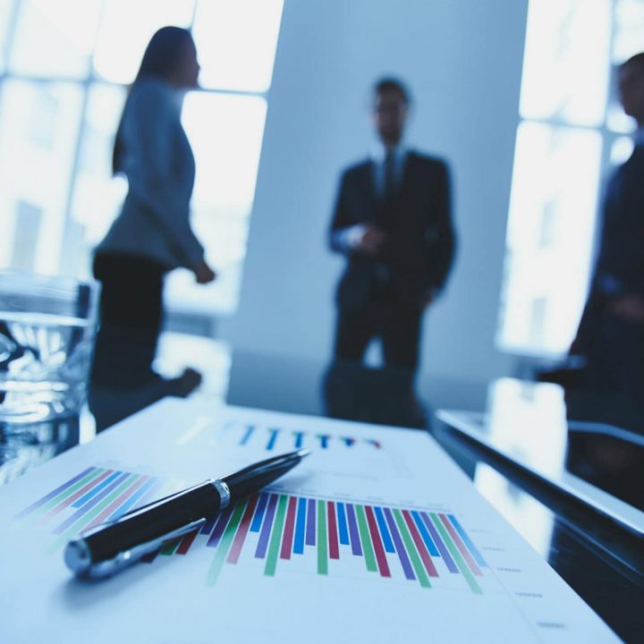 paper on desk with business people in background