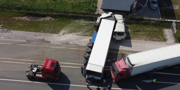 Aerial view of a traffic accident involving three large trucks, with one jackknifed across the road and two others stopped nearby.